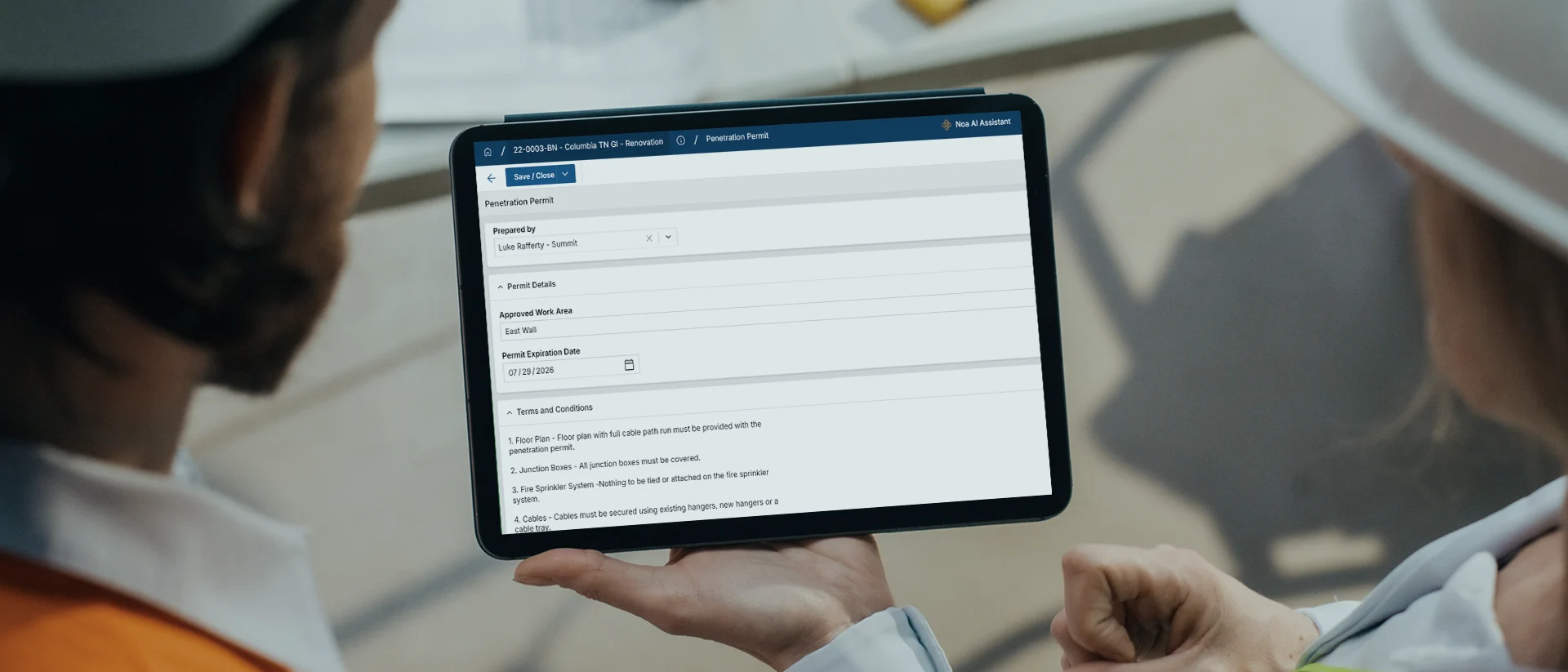 Two people in safety gear view a tablet displaying a checklist or form interface related to preventive maintenance tasks in a professional setting.