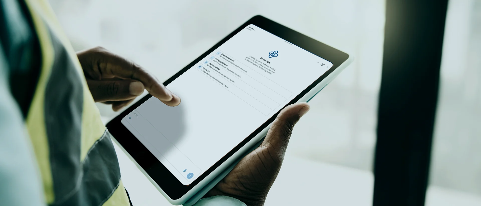 A person uses a tablet, interacting with an application on the screen in a bright room. The display shows a form or checklist with a logo at the top.