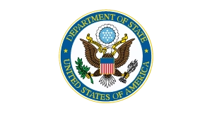 The official seal of the U.S. Department of State, featuring a bald eagle holding an olive branch and arrows, with a blue and white shield and a circle labeled “Department of State United States of America.”.