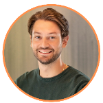 Smiling man with brown hair and a beard, wearing a dark green shirt. He is photographed against a blurred, light background and framed by an orange circular border.