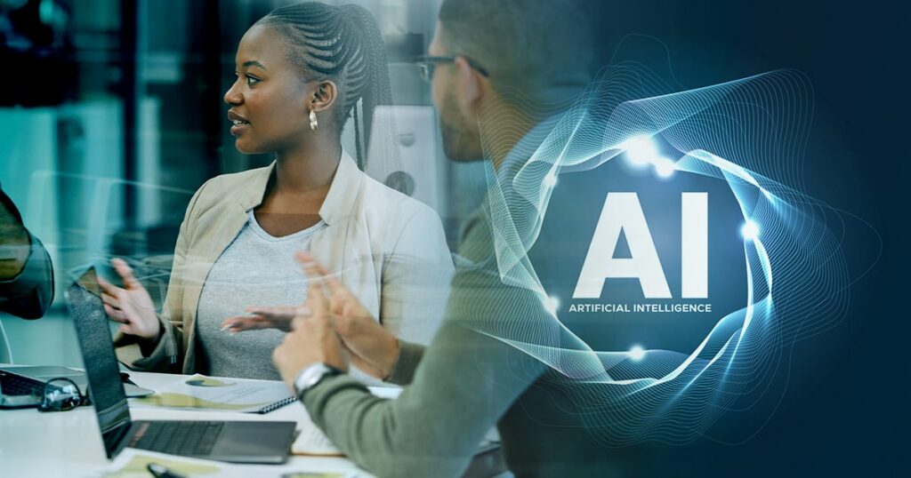 Two people have a discussion at a desk with laptops; a glowing graphic shows AI ARTIFICIAL INTELLIGENCE with digital network lines on the right side of the image.