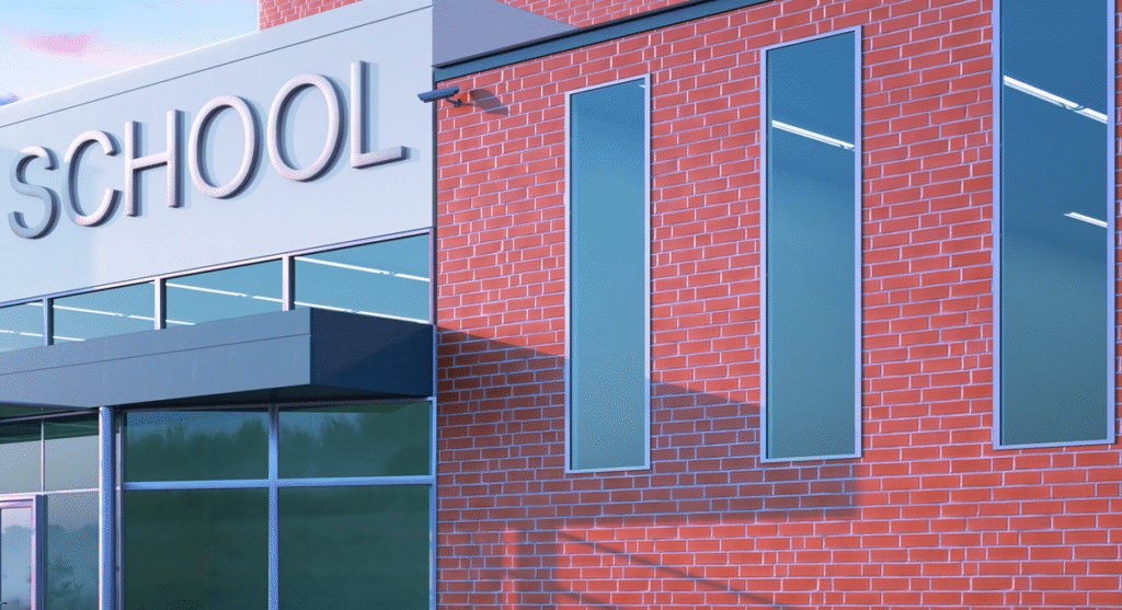 Modern brick school building with large vertical windows and the word SCHOOL displayed on the exterior wall; clear blue sky is visible in the background.