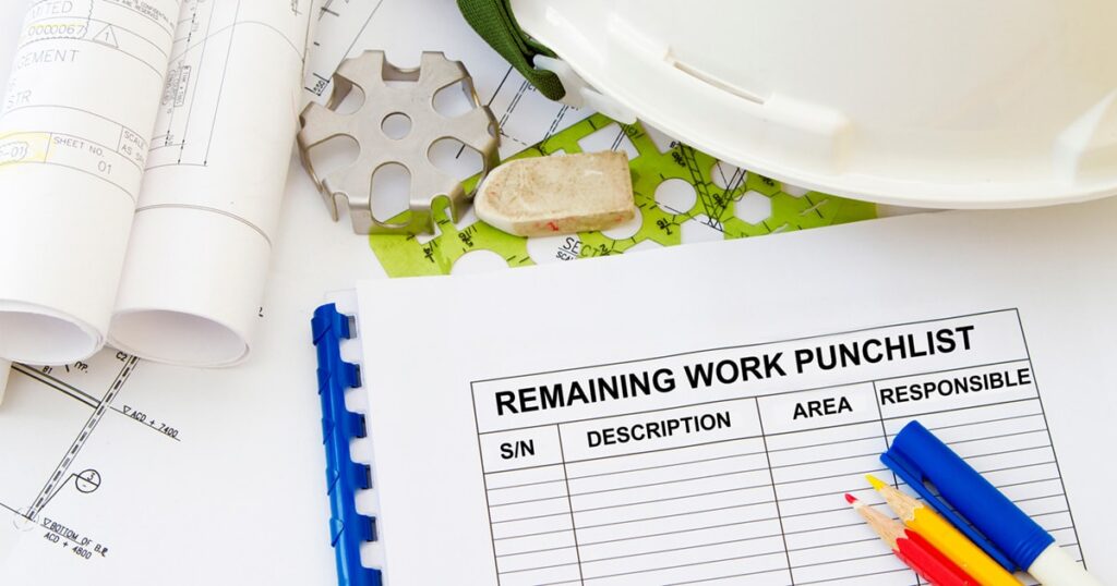 A construction punchlist form on a desk with blueprints, a hard hat, colored pencils, eraser, and a metal mechanical part.