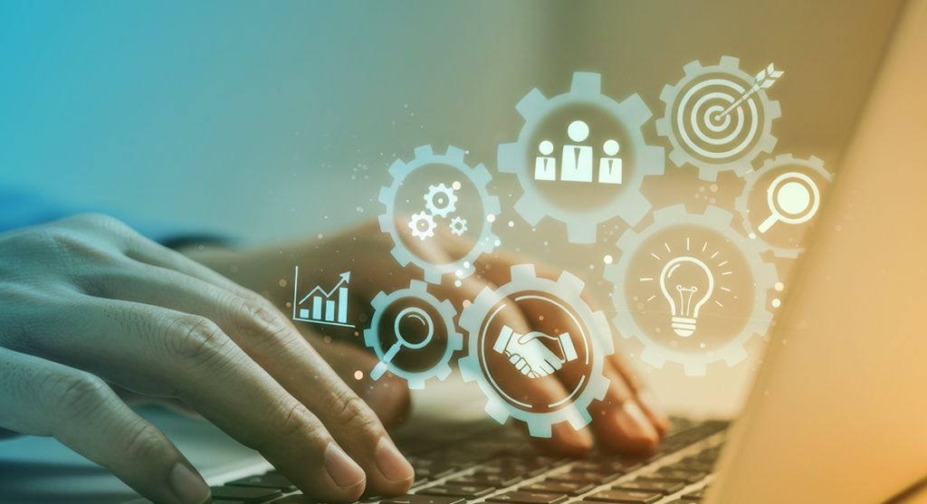 Hands typing on a laptop keyboard with translucent business and technology icons, such as gears, graphs, a lightbulb, magnifying glass, handshake, and target, overlaid on the image.