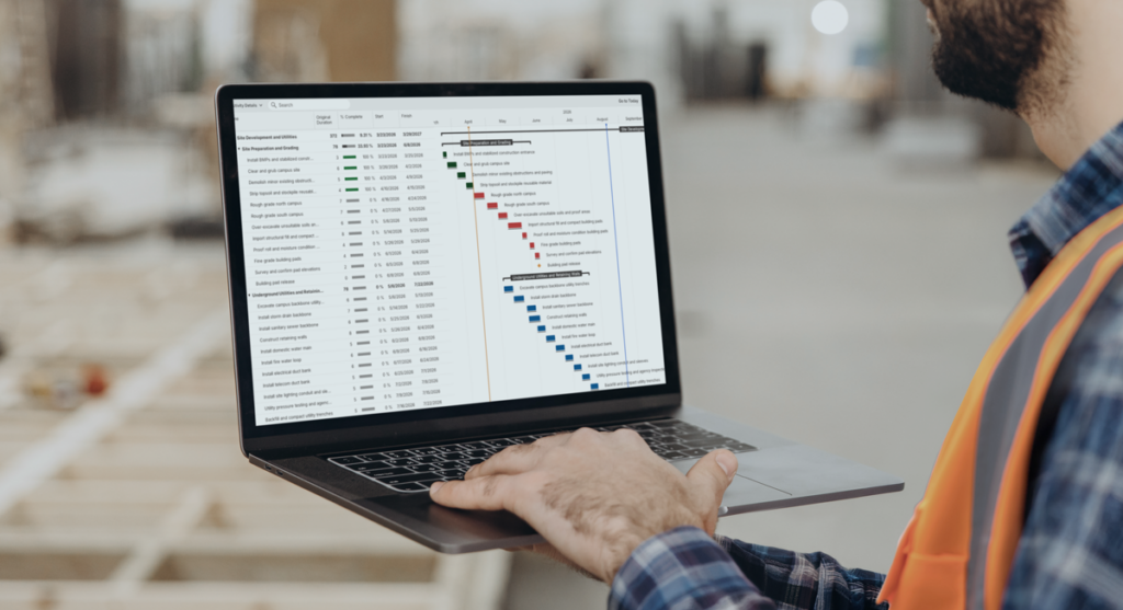 A construction worker in a high-visibility vest holds a laptop displaying a project schedule Gantt chart.